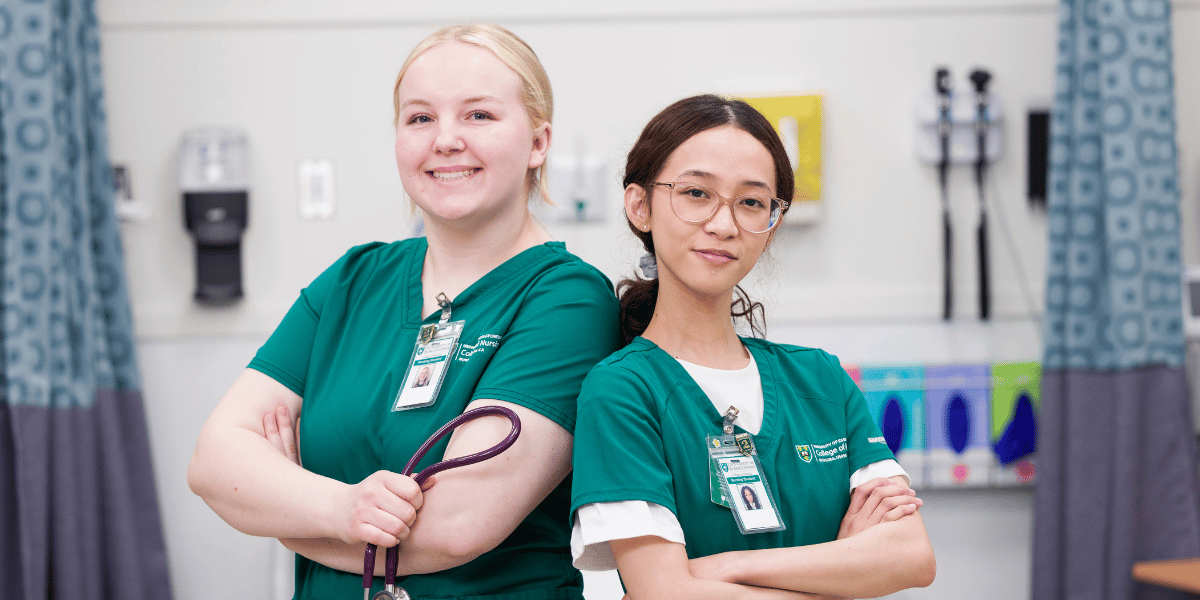 Two female nursing students standing back to back with their arms crossed