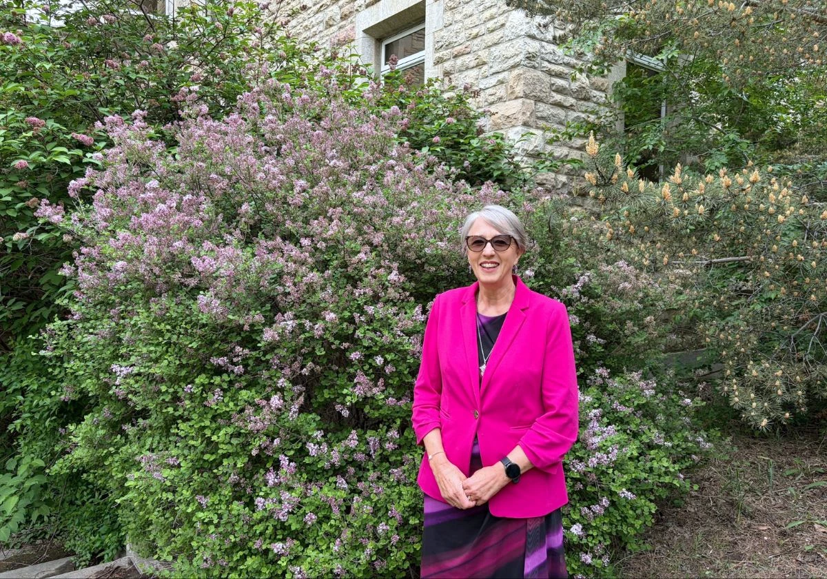 Dr. Solina Richter stands in front of a building and trees smiling for the camera.