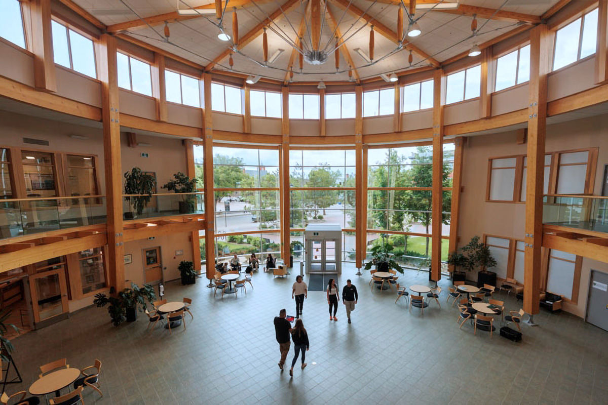 People walking through the main Prince Albert Campus atrium lobby set up with tables and chairs.