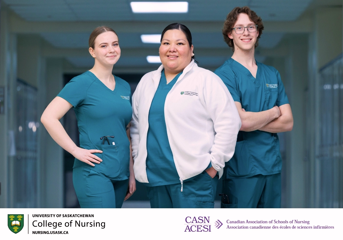 Three nursing students standing in scrubs posing for a photo in a hallway.